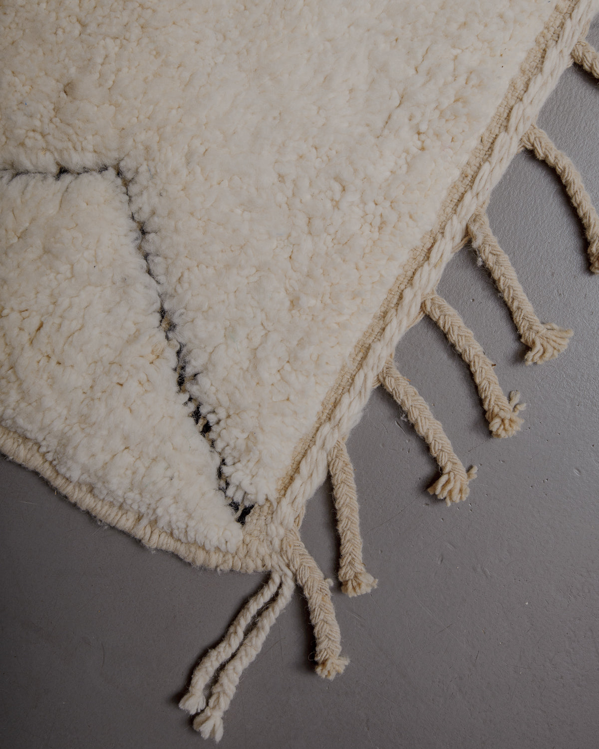 Edge of cream beniourain rug with natural wool tassels.