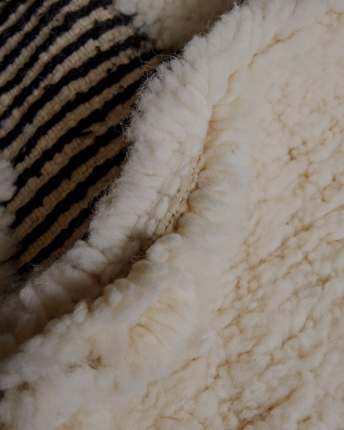 Fluffy cream wool pile with black striped details.