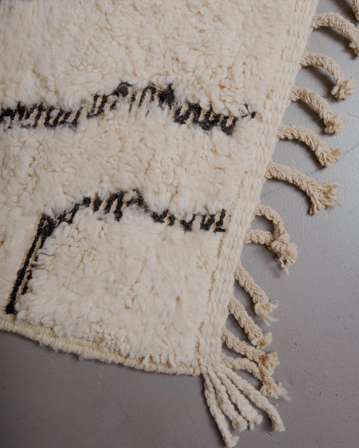 Edge of cream beniourain rug with natural wool tassels.