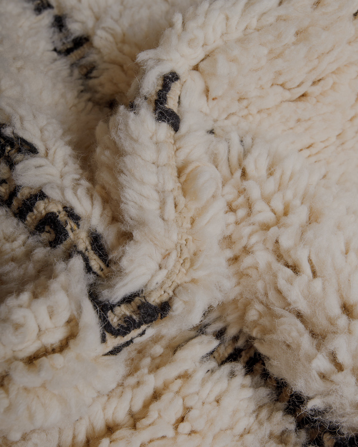 Fluffy cream wool pile with black embroidered details.