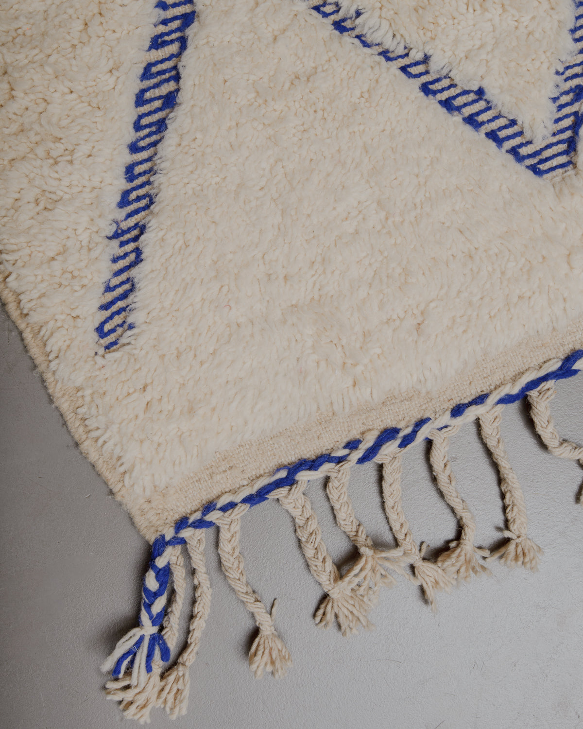 Corner of Berberlin rug with wool tassels along the edge.