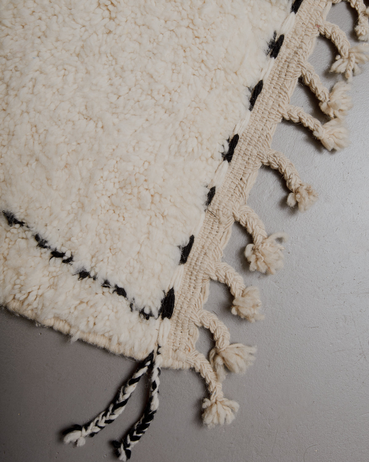 Corner of Berberlin rug with wool tassels along the edge.
