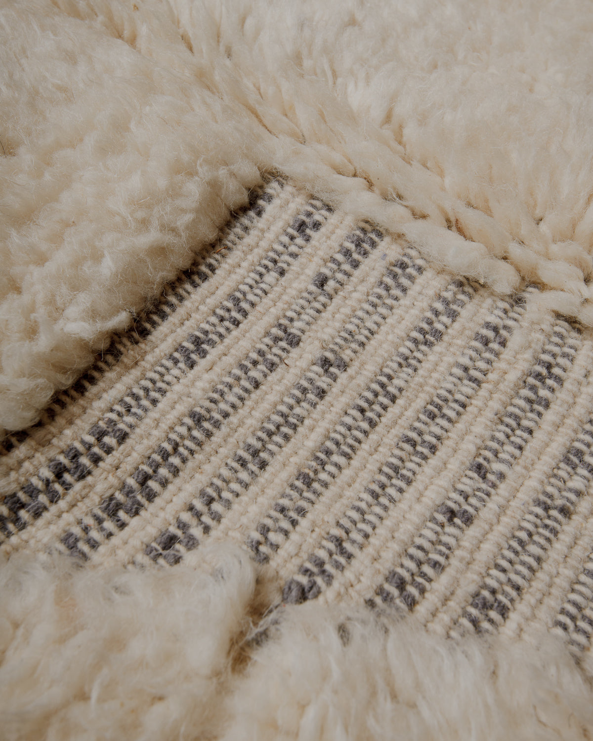 Fluffy cream wool pile with grey details.
