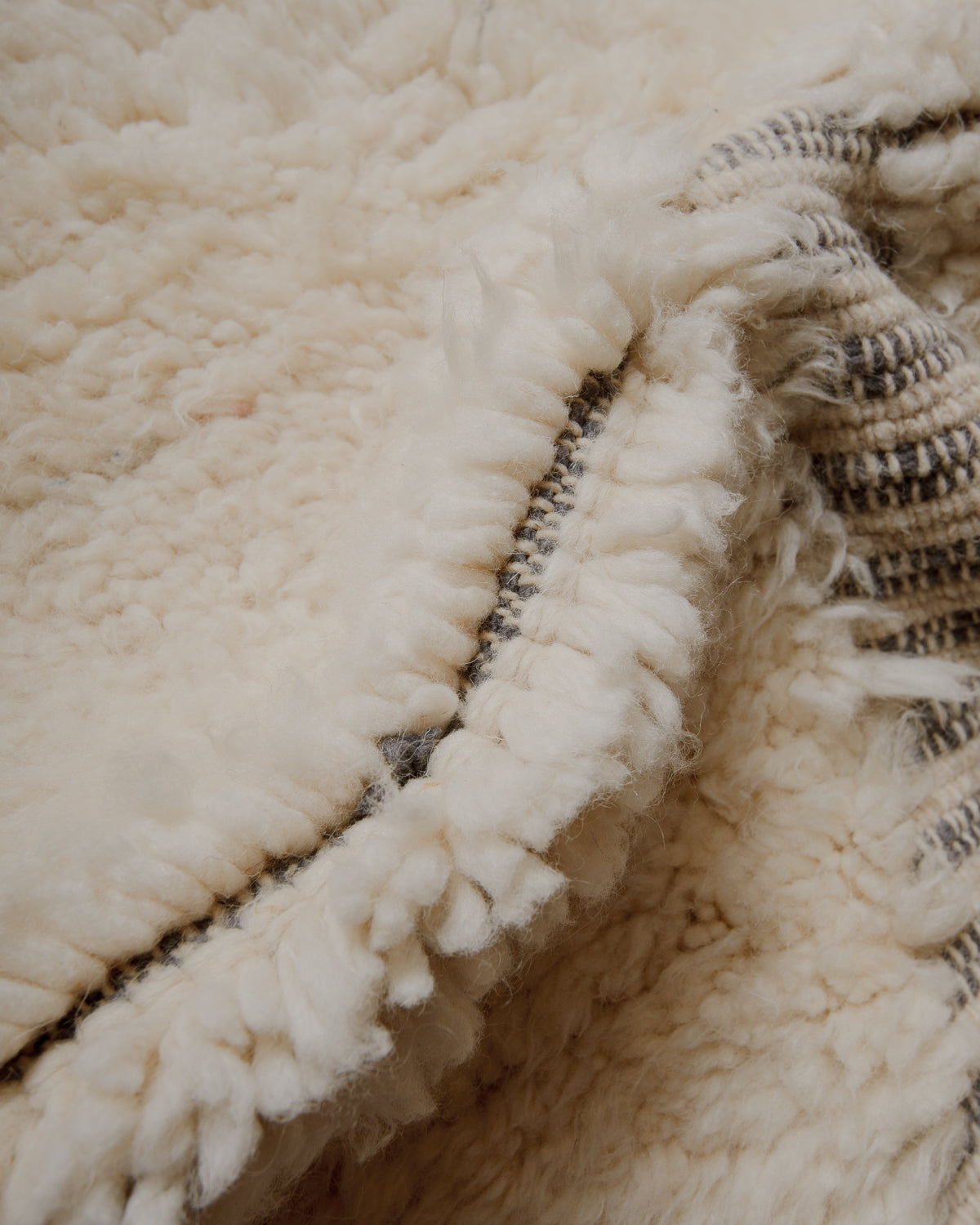 Fluffy cream wool pile with grey details.
