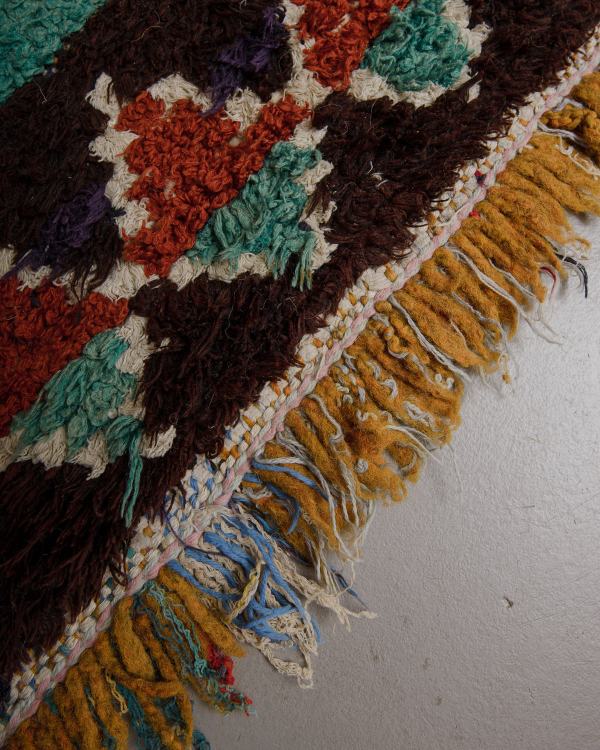 Close up of vintage rug made of wool and colourful cotton with a fluffy, shaggy texture and a fringe of mixed textile.