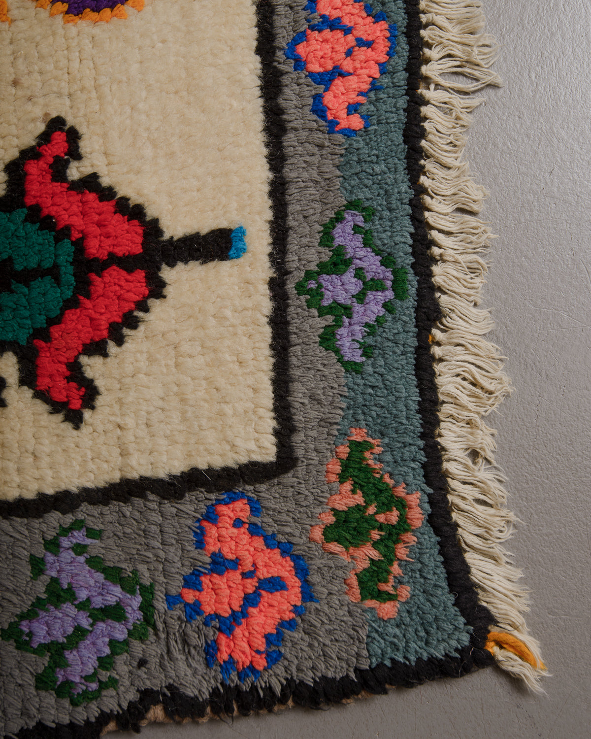 Corner of rug made of wool and colourful cotton with cream fringe along the edge.