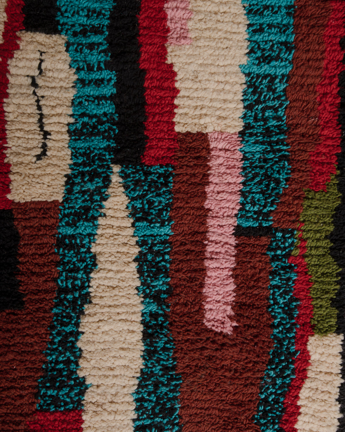 Surface of Boujaad rug with blue, black, red, brown, pink, cream and khaki wool.