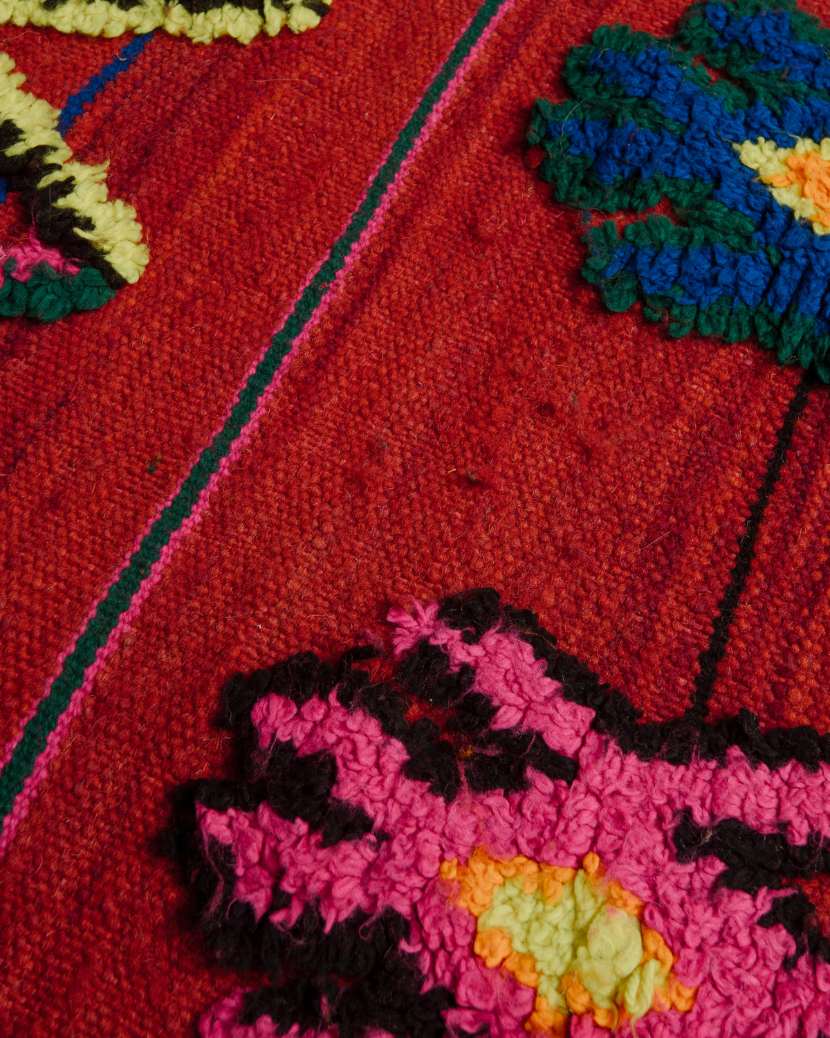 Surface of flat woven wool kelim rug with fluffy embroidered details in colourful cotton.