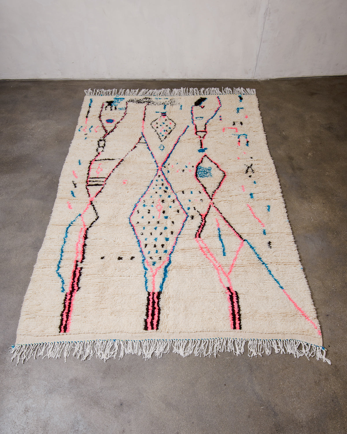 Berberlin Azilal rug made of fluffy wool and cotton, laying flat on a concrete floor. 