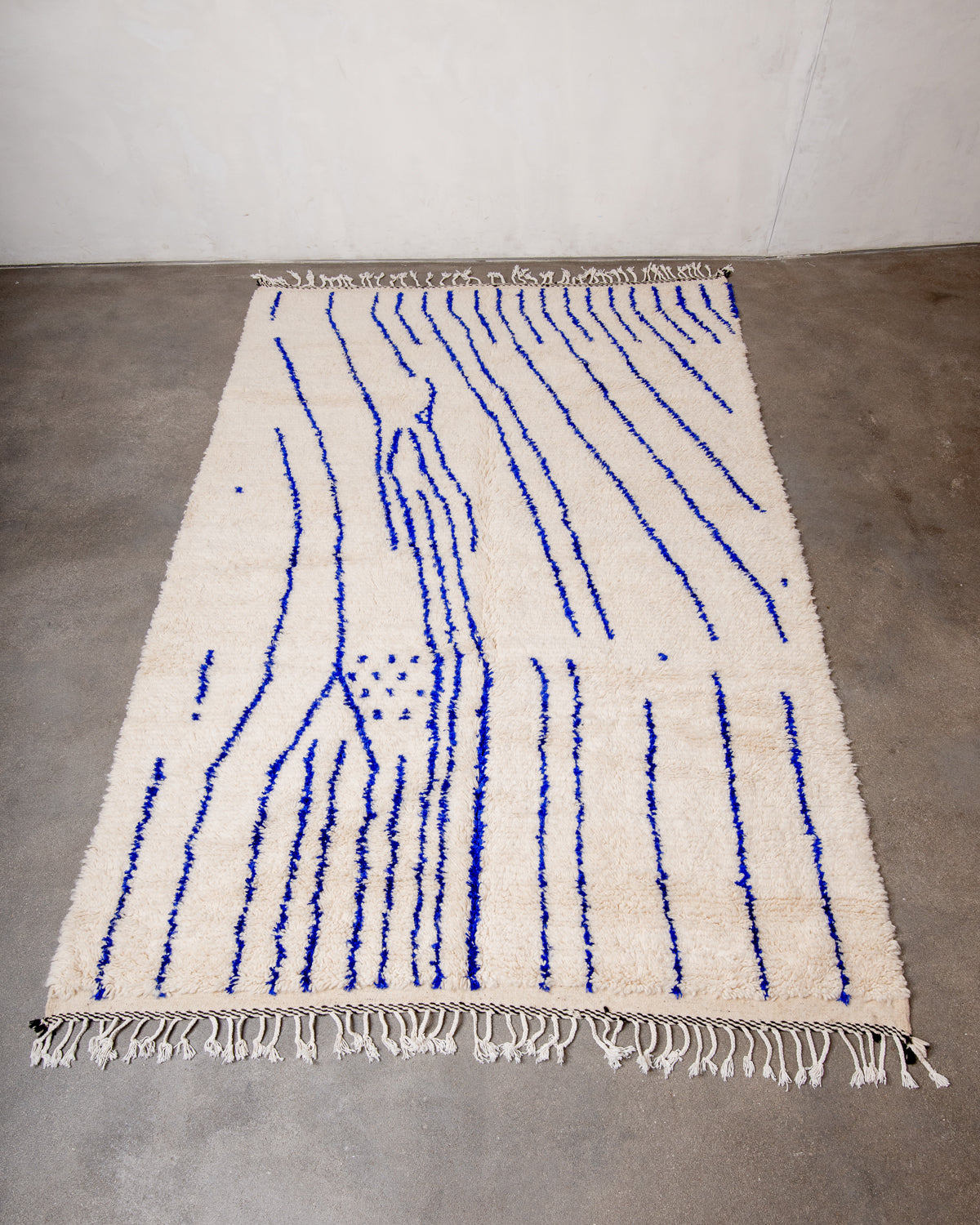 Berberlin Azilal rug made of fluffy wool and cotton, laying flat on a concrete studio floor. 