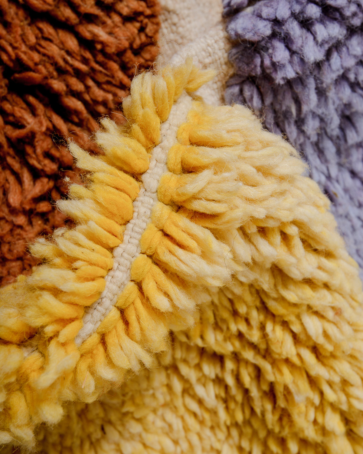 Detail of fluffy knotted wool in yellow, lavender and brown.