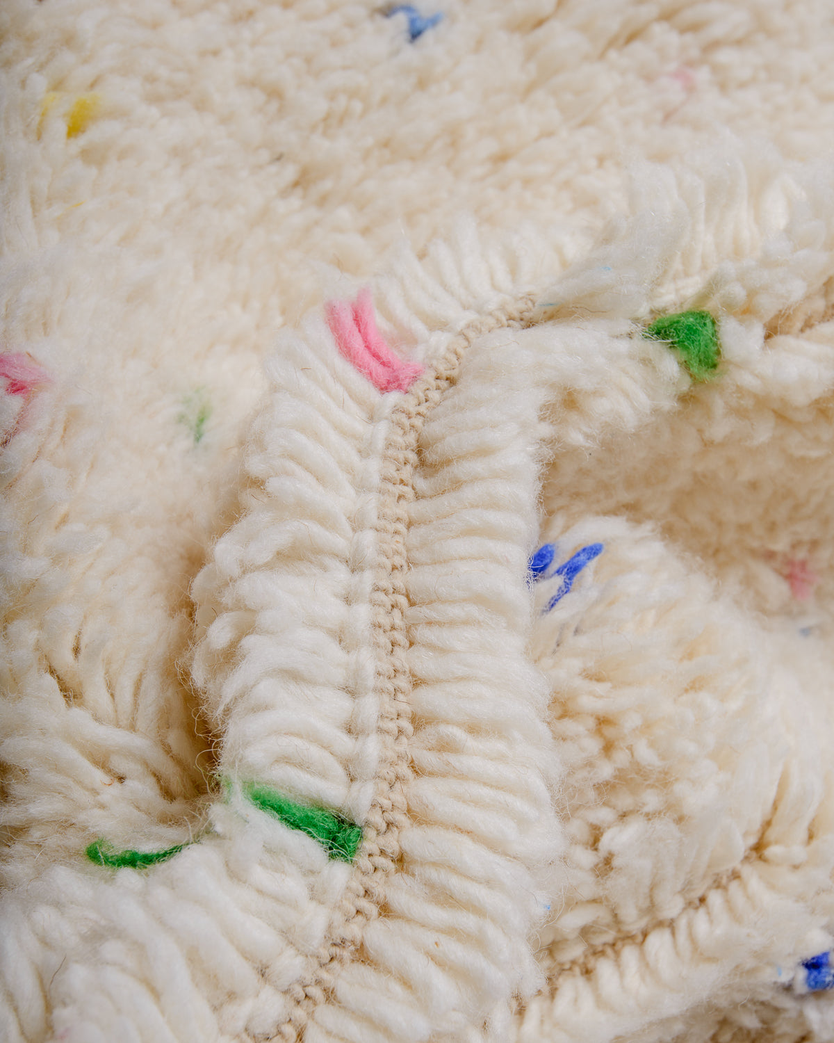 Detail of cream wool rug showing the density of the wool and coloured strands that make up the polka dots. 
