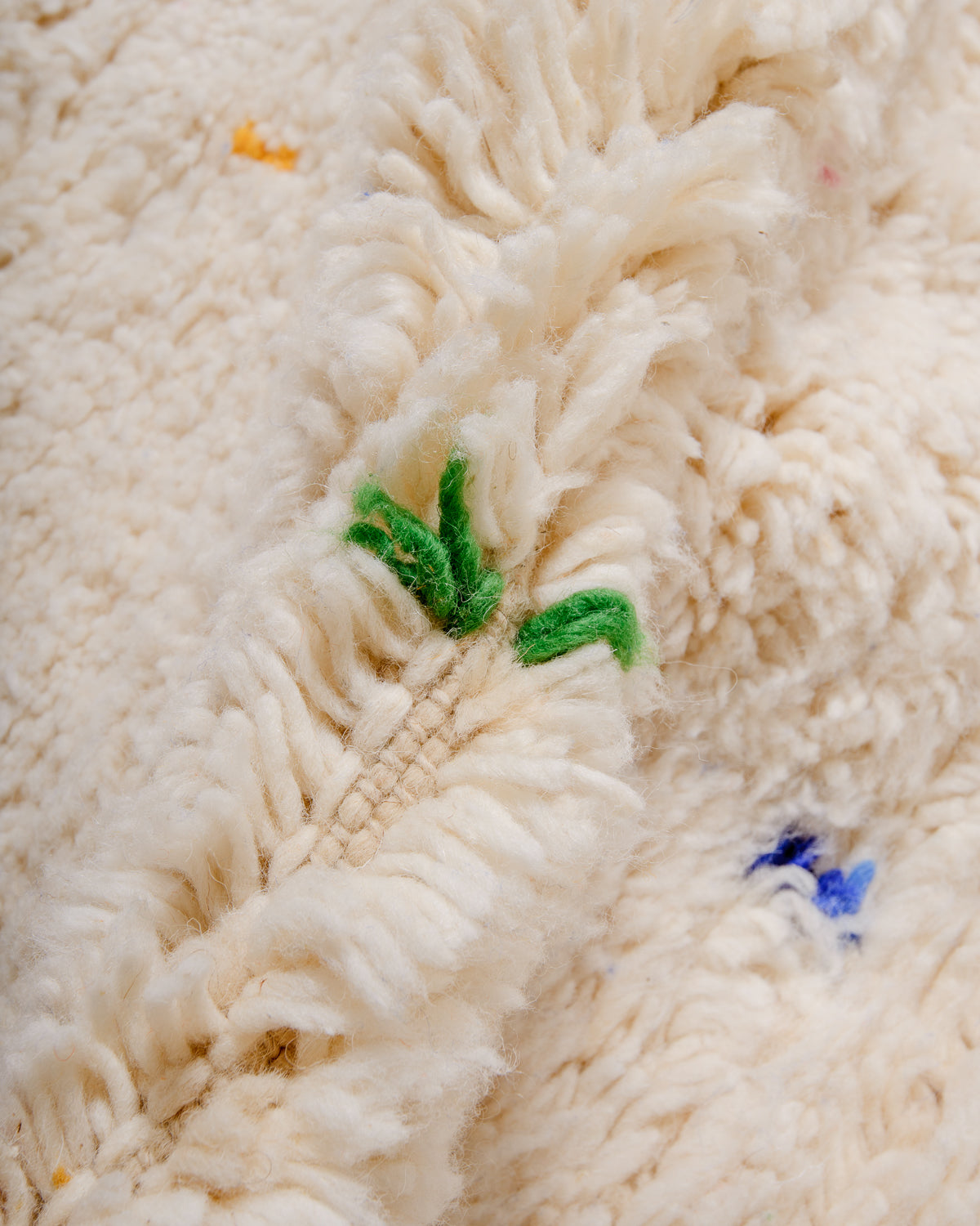 Detail of cream wool rug showing the density of the wool and coloured strands that make up the polka dots. 