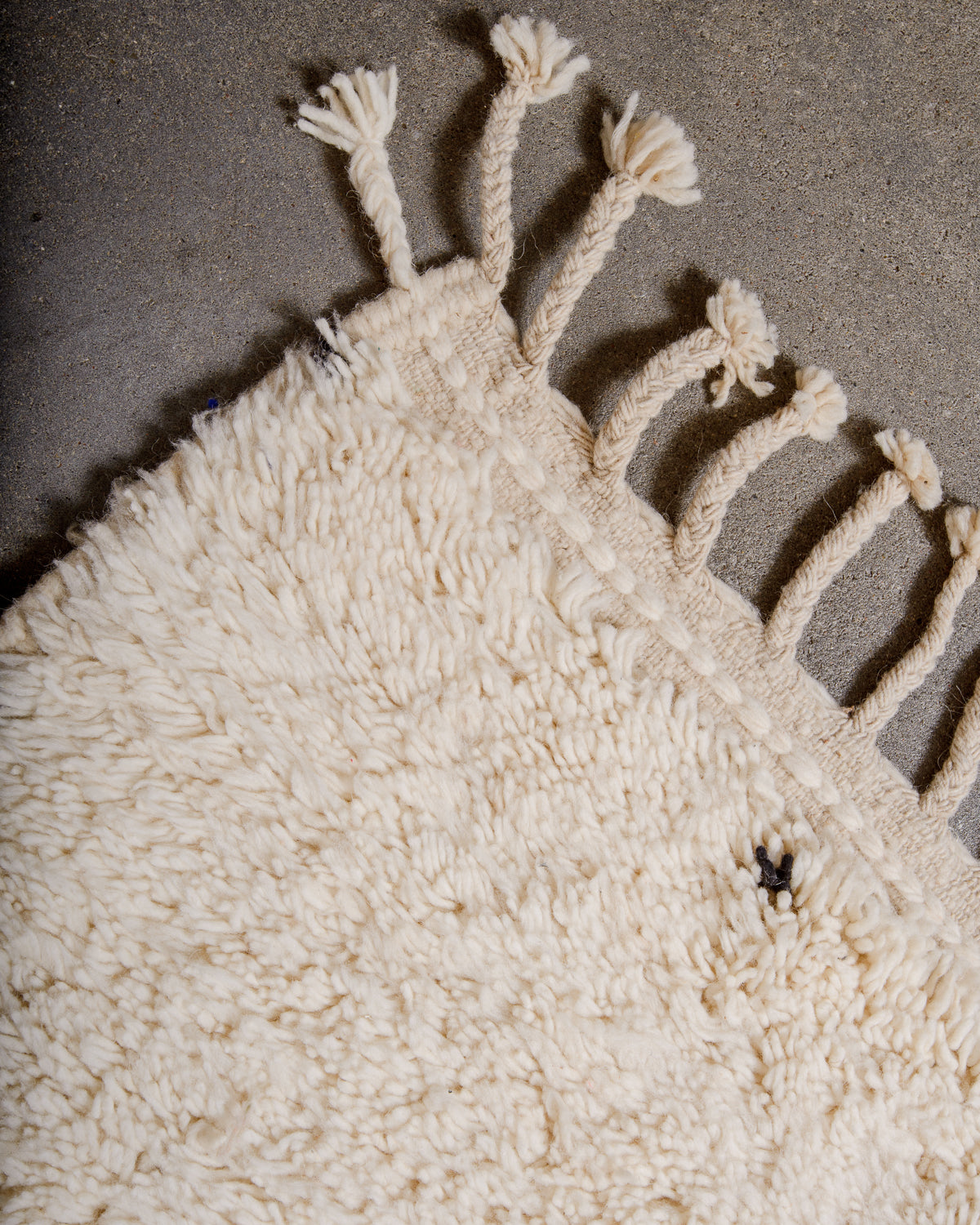 Corner of Berber rug with natural wool tassels across the top. 