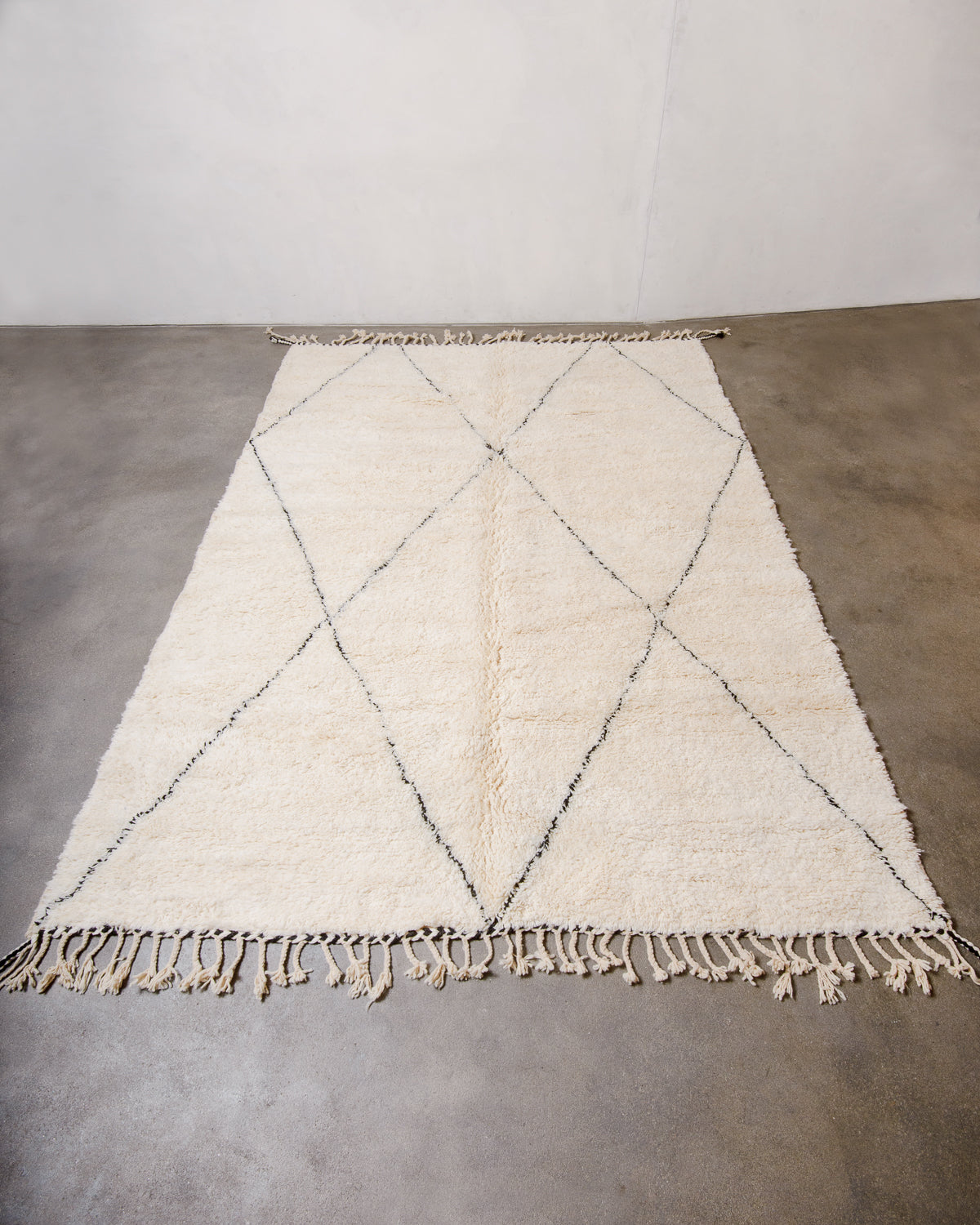 Cream Berber rug with black diamond design laying flat on floor. 