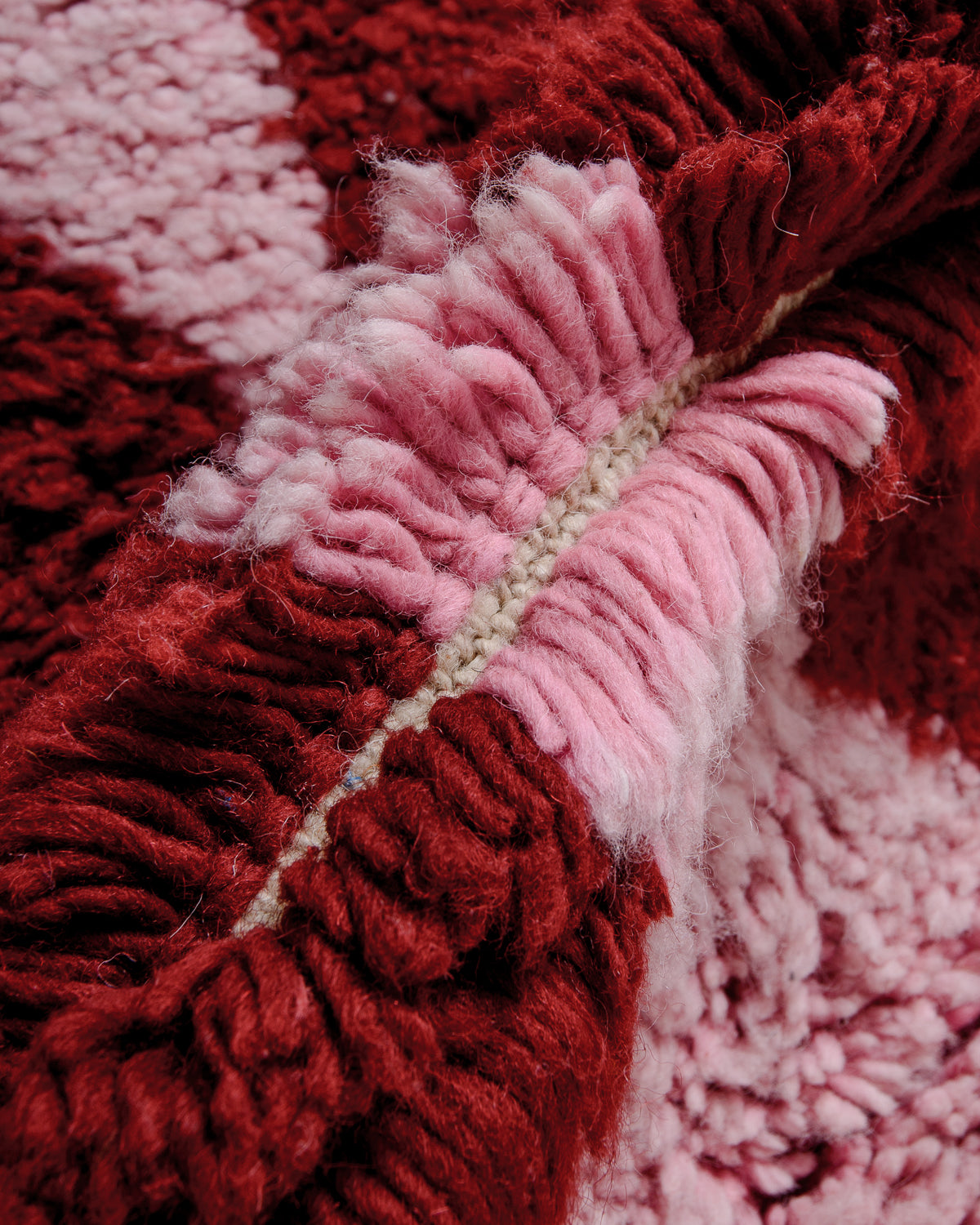 Detail of Berberlin Beni Ourain rug showing depth of pile and fluffy pink and burgundy wool. 