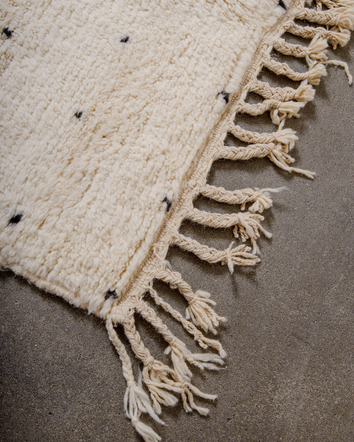 Corner of Berber rug with natural wool tassels across the top. 
