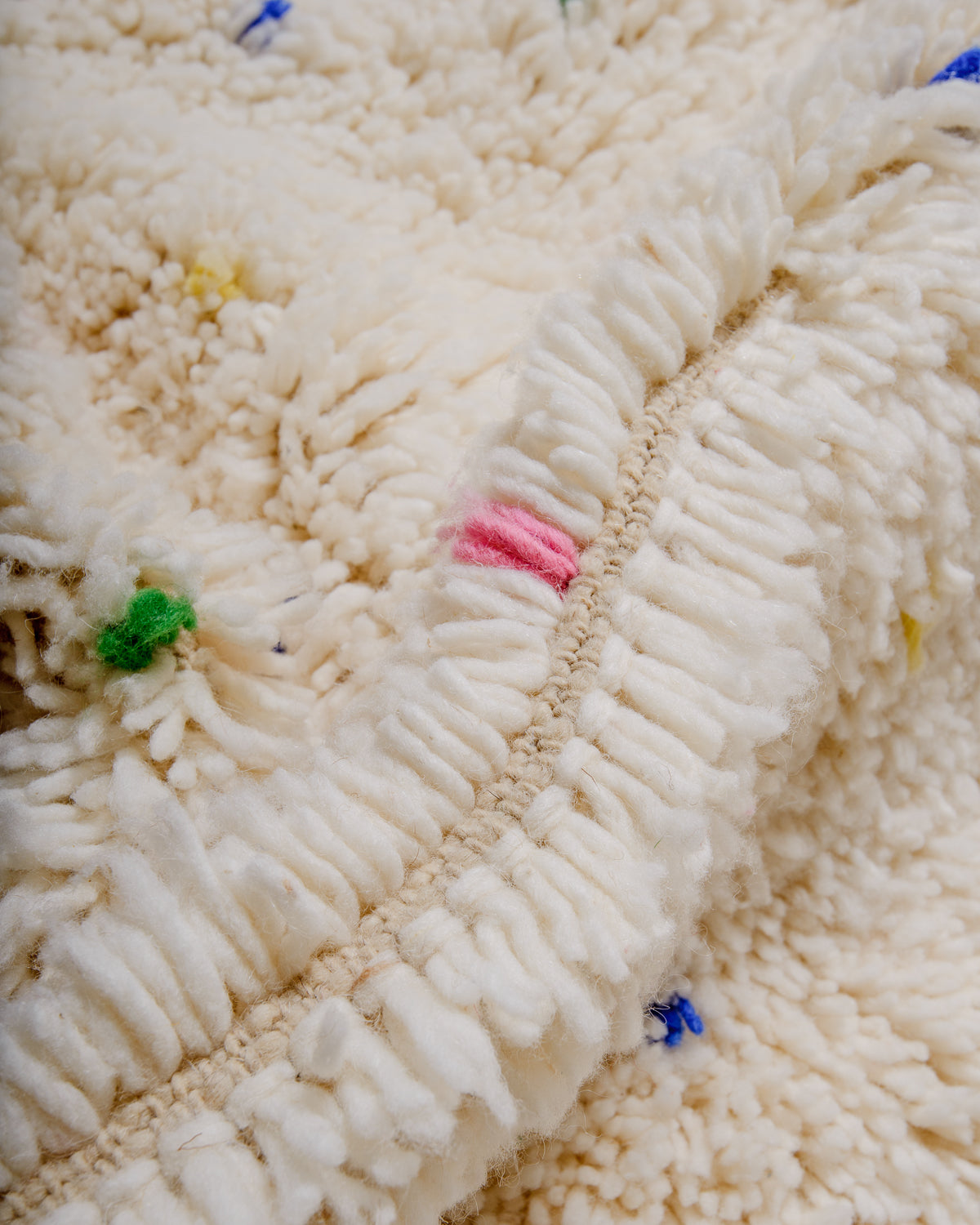 Detail of cream wool rug showing the density of the wool and coloured strands that make up the polka dots. 