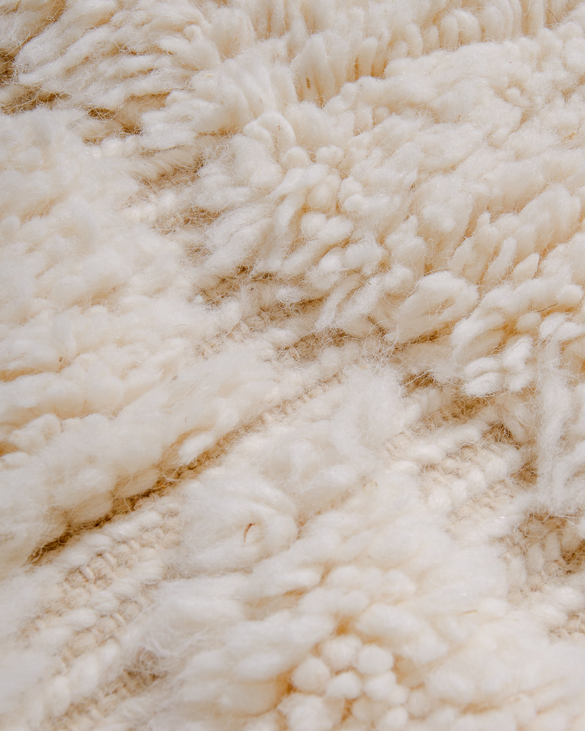 Detail of cream wool rug with woven design elements.