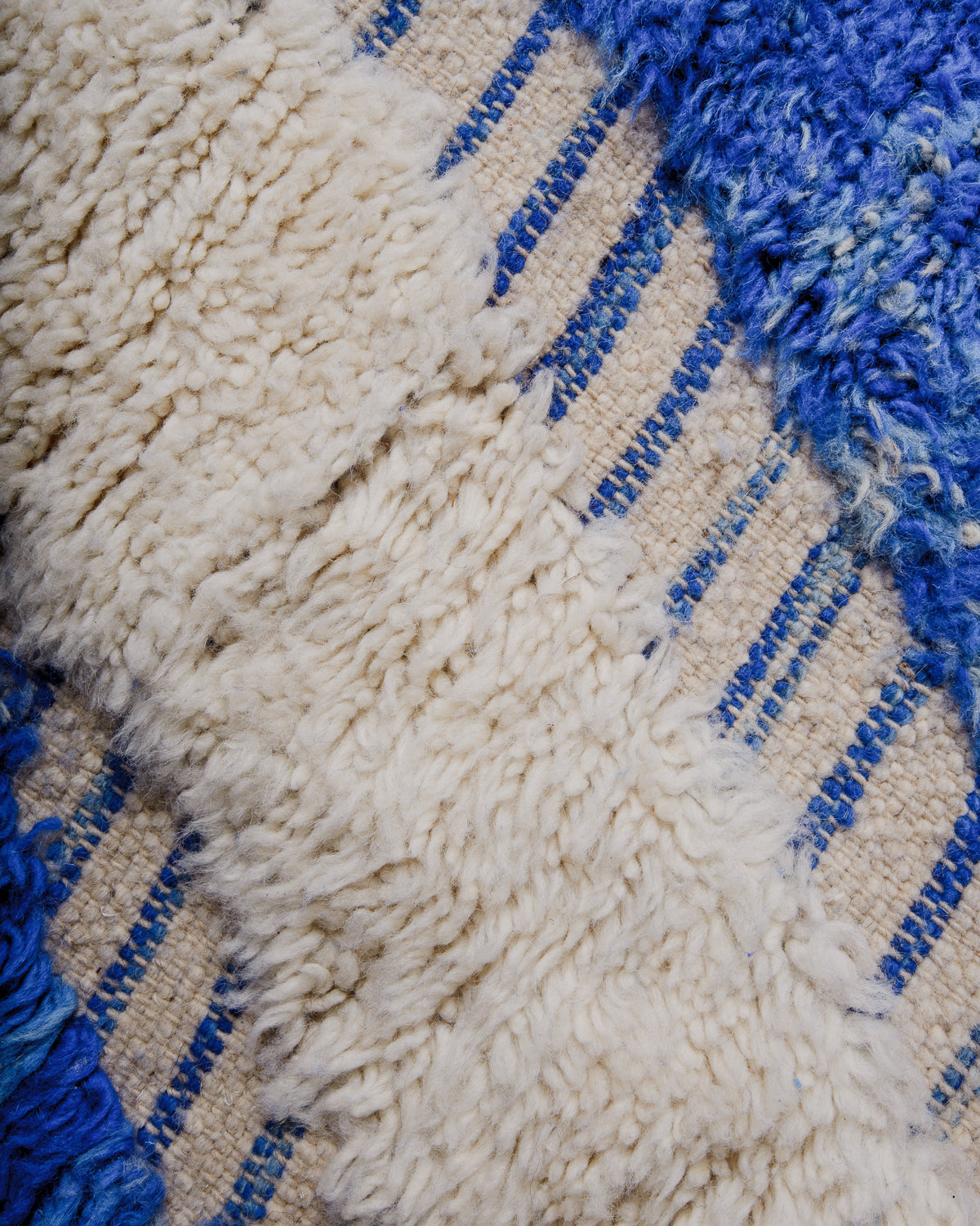 Detail of beniourain rug in blue and cream with mix of fluffy wool pile and flat woven areas. 