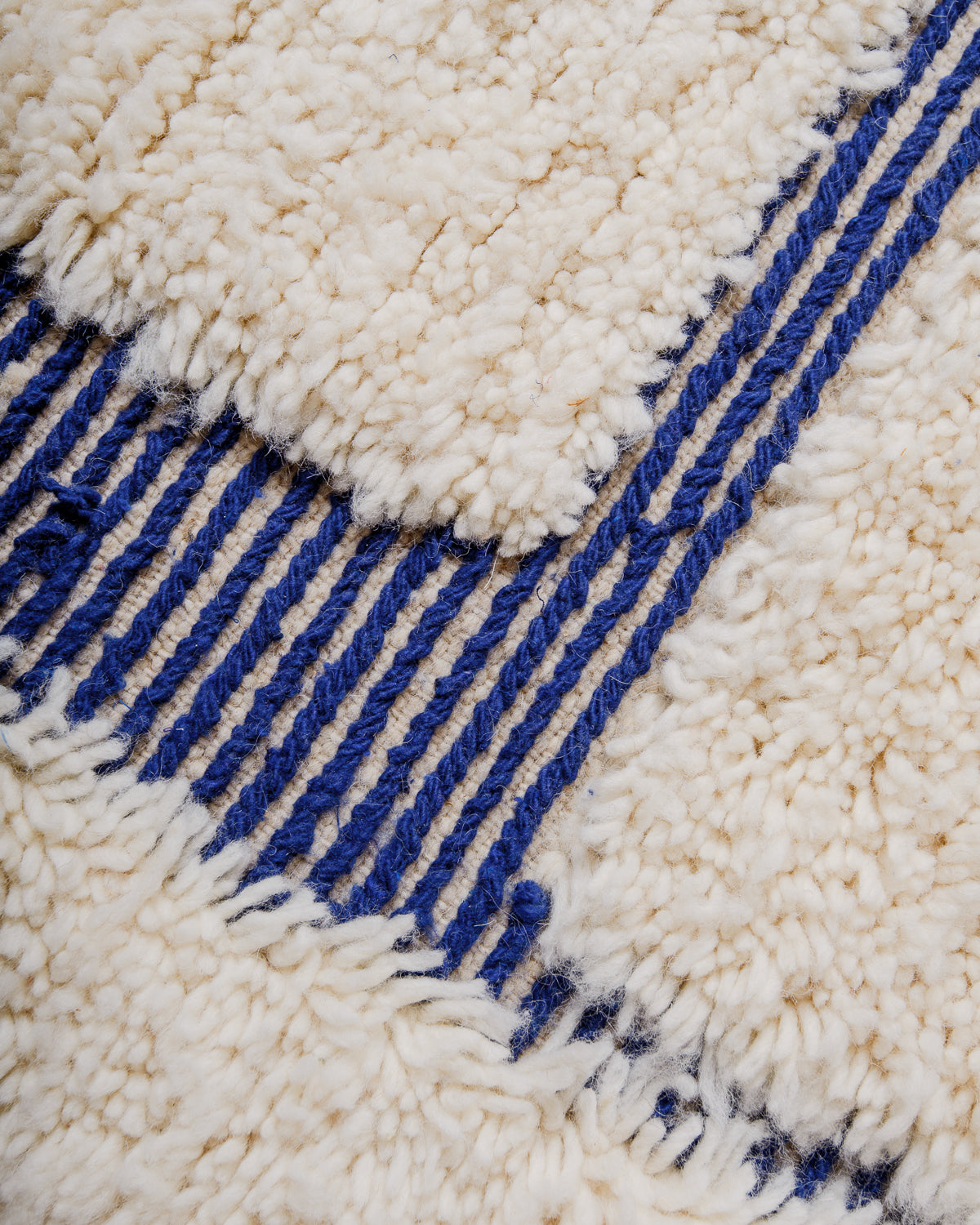 Detail of beniourain rug in blue and cream with mix of fluffy wool pile and flat woven areas. 