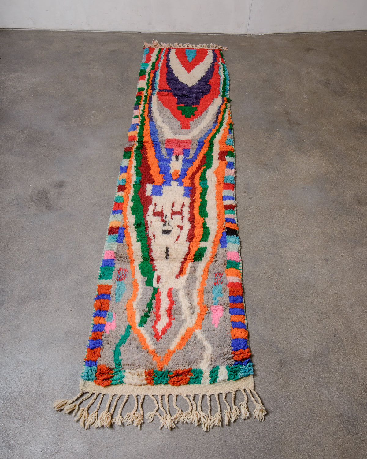 Berberlin vintage runner rug made of brightly coloured wool, laying flat on concrete floor. 