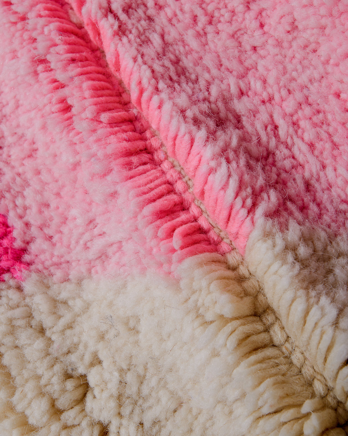 Detail of pink and cream wool of Berberlin finest Beniourain rug showing thick wool pile and dense knots.