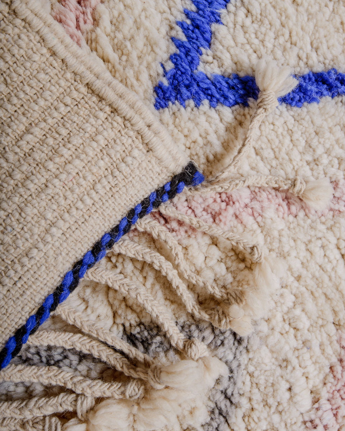 Corner of rug folded over to show the back and density of rows of knots.