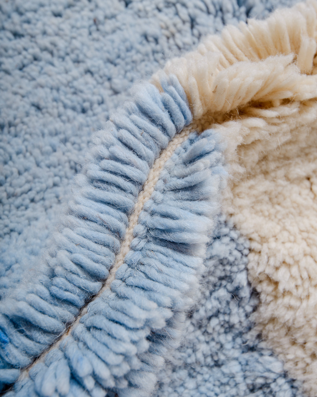 Detail of blue and cream wool of Berberlin finest Beniourain rug showing thick wool pile and dense knots.