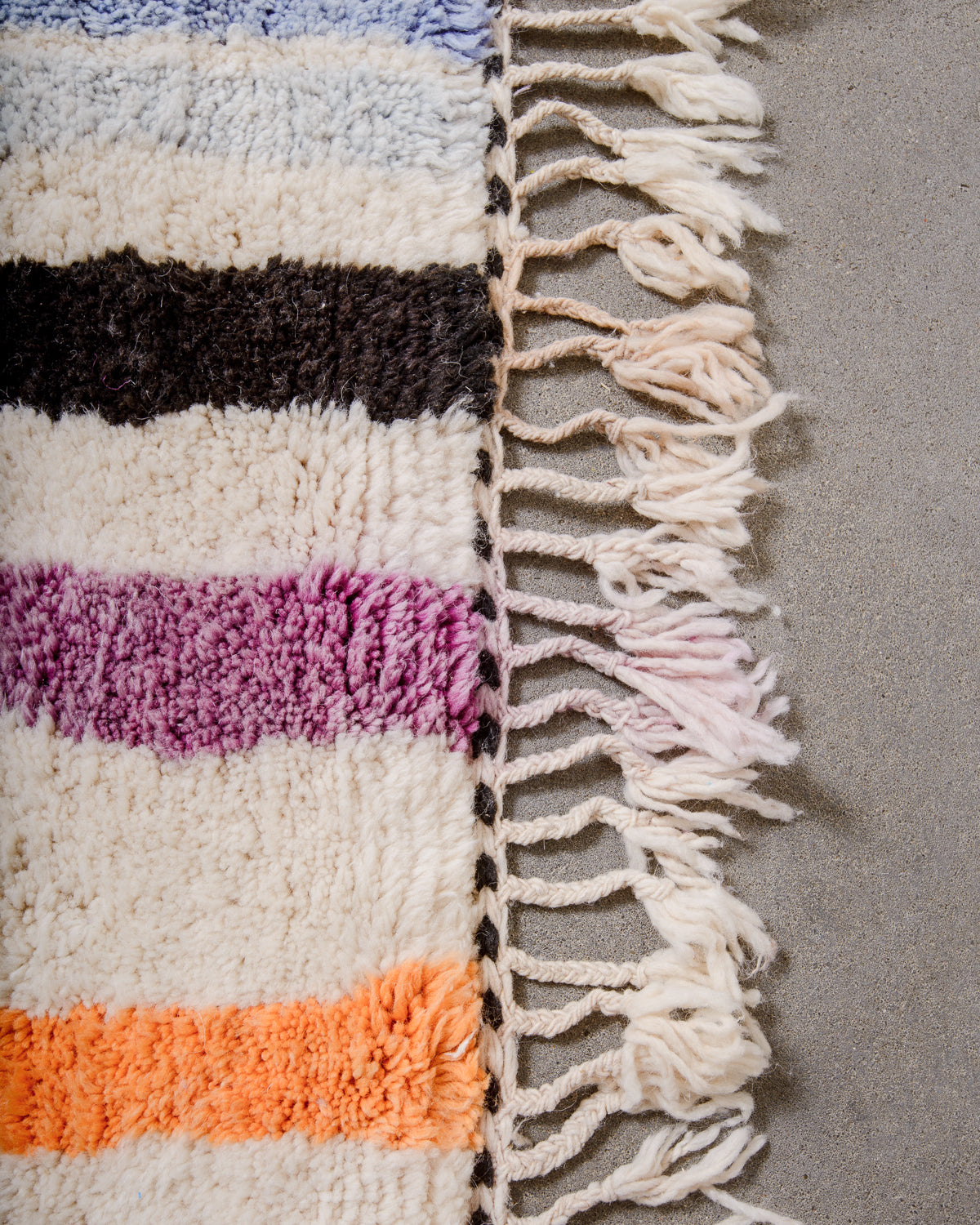 Edge of rug finished with natural wool tassels. 