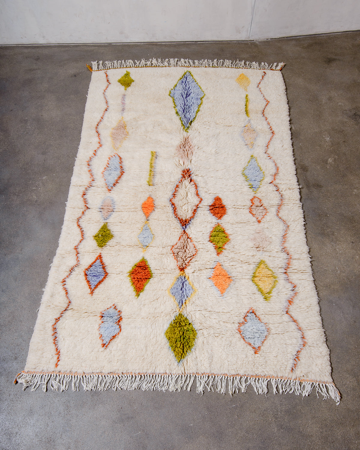 Berberlin Finest Rug made of plush cream wool with a charming design, laying flat on concrete floor. 