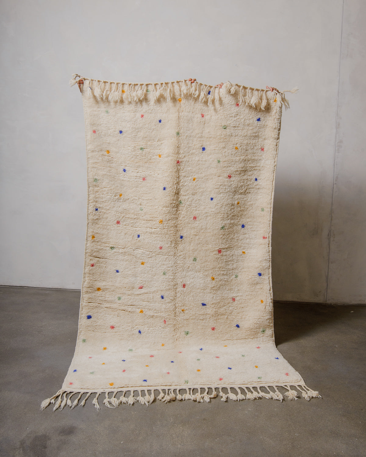 Cream wool rug with colourful polka dots on a plain background