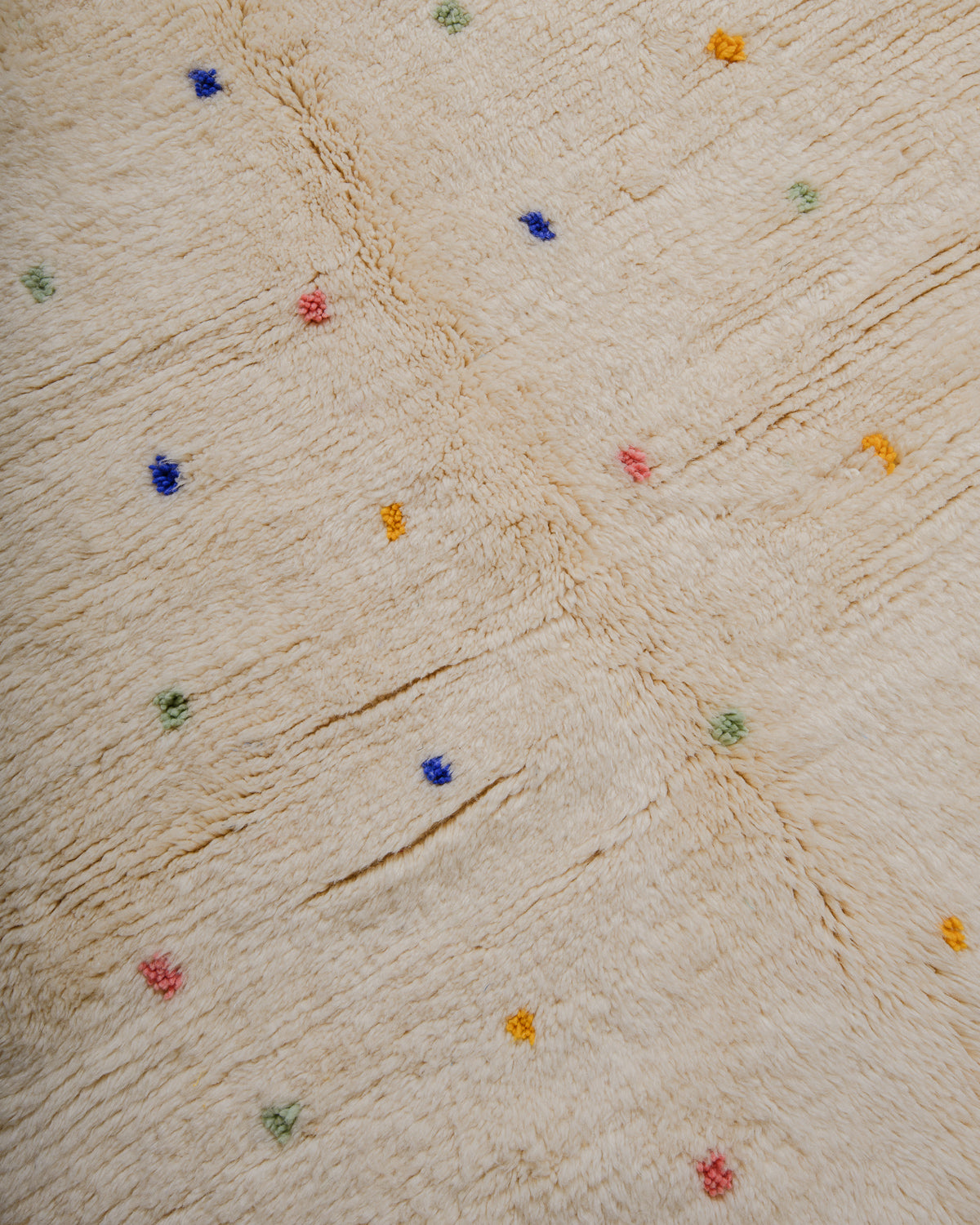 Surface of wool rug with colourful dots and a thick pile.