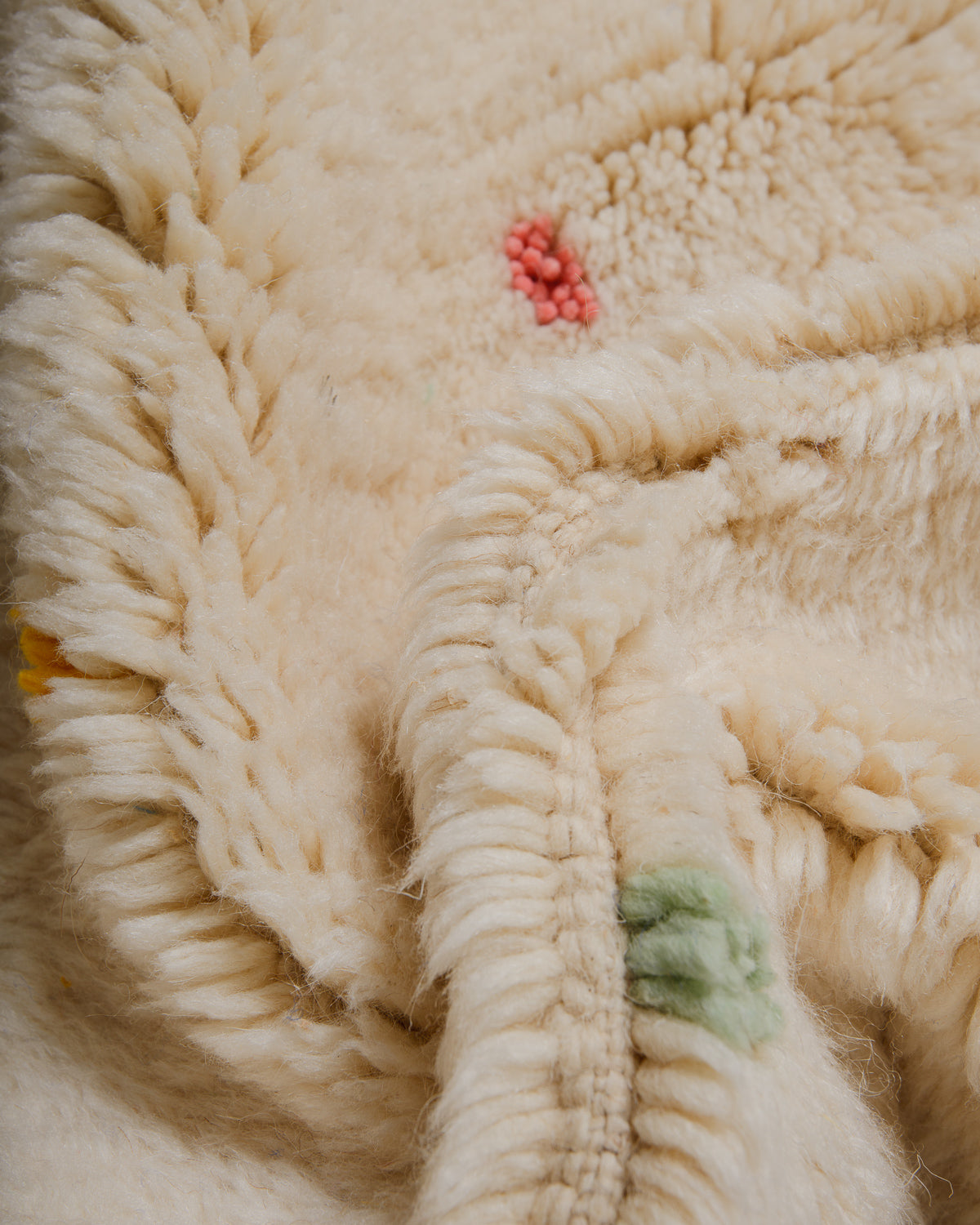 Close-up of textured cream rug with dense pile and colourful dots. 
