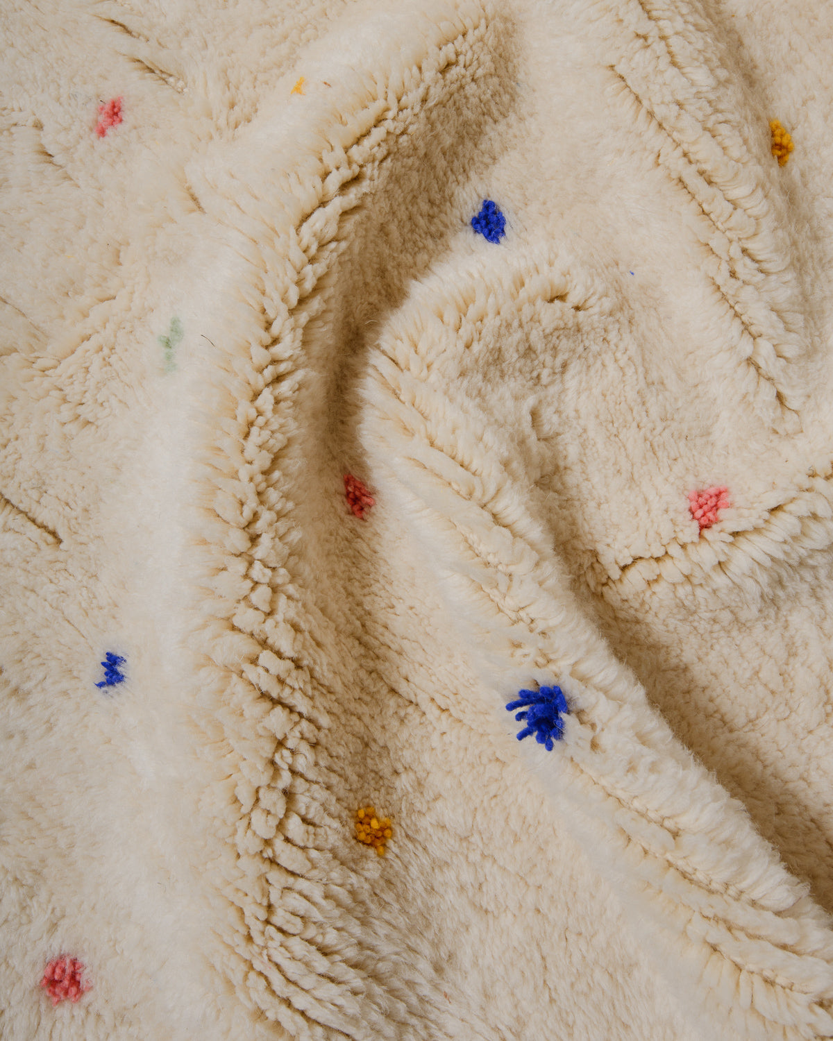 Close-up of cream wool rug with colourful dots.