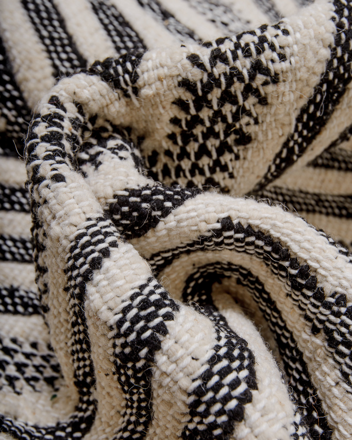 Bunched up black and white flat-woven kelim rug showing the texture of the weave.