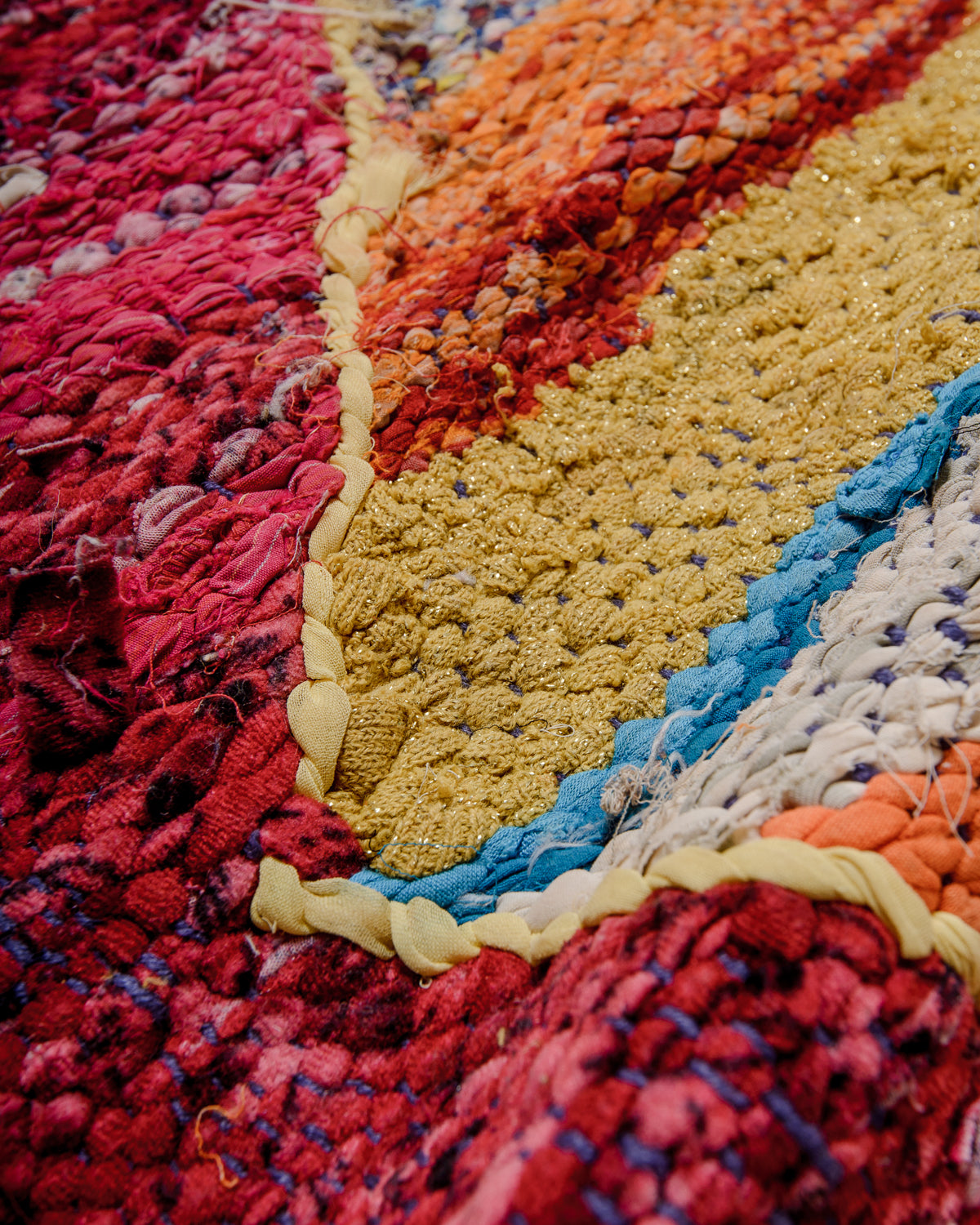 Different textures on the surface of a Berber Kelim rug in glittery yellow, red, white and blue. 