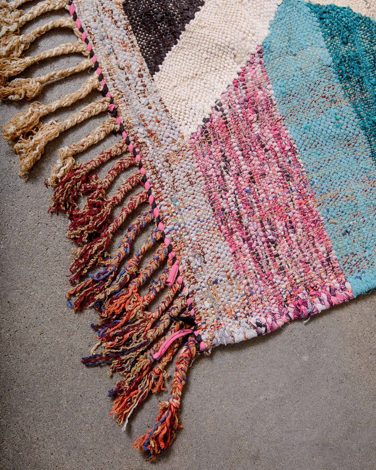 Corner of vintage kelim rug with cotton tassels in different colour combinations. 