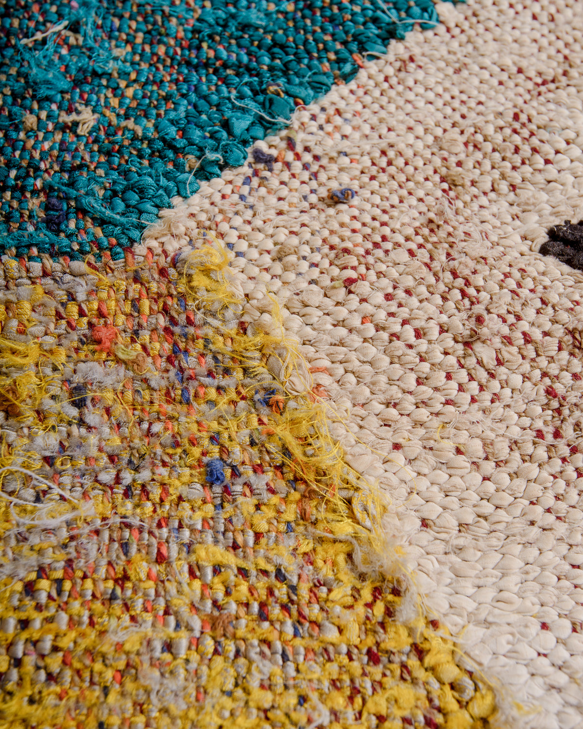 Different textures on the surface of a Berber Kelim rug in yellow, white and turquoise. 