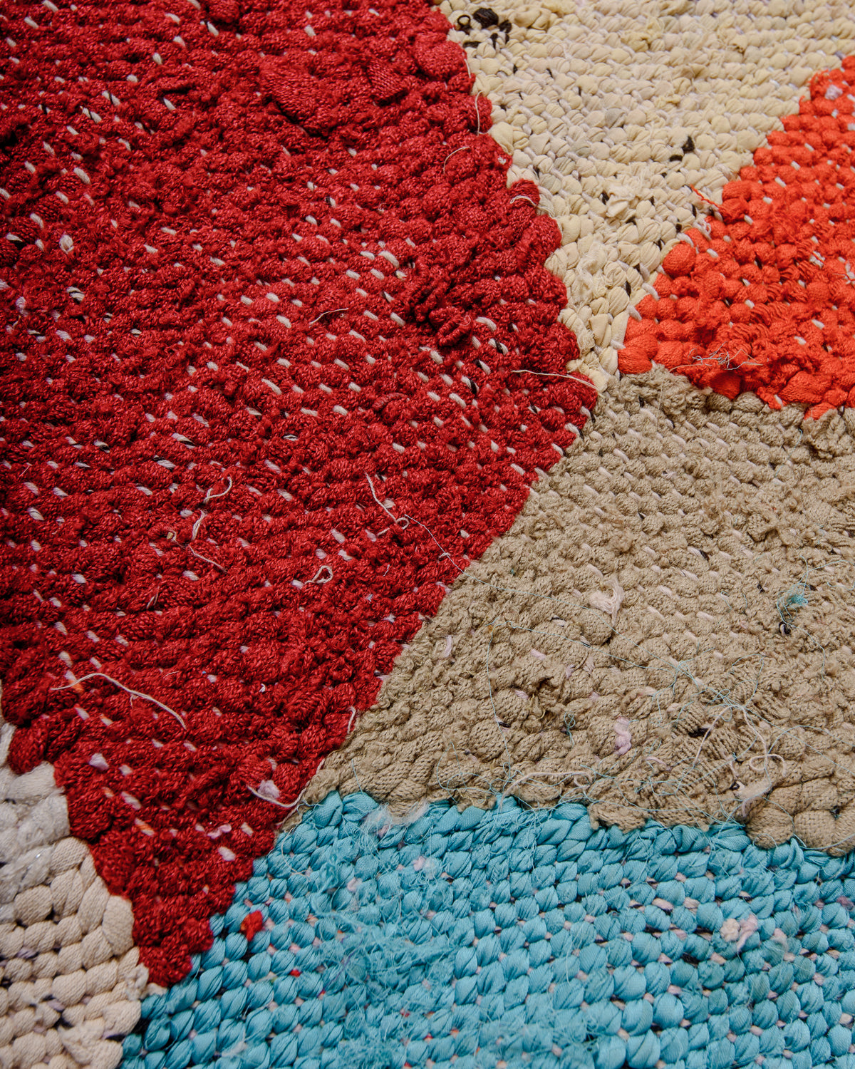 Texture of vintage Kelim rug made of recycled cotton and fabric remnants, in shades of red, taupe, blue and butter.