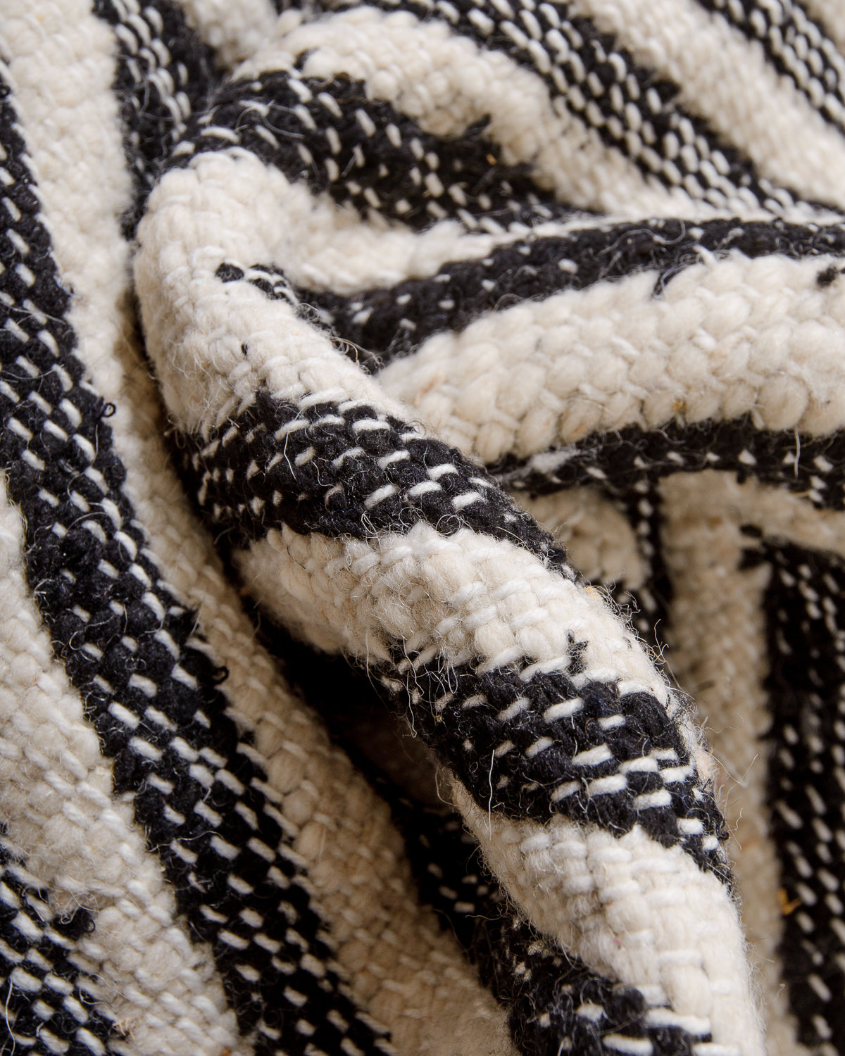 Bunched up black and white flat-woven kelim rug showing the texture of the weave.
