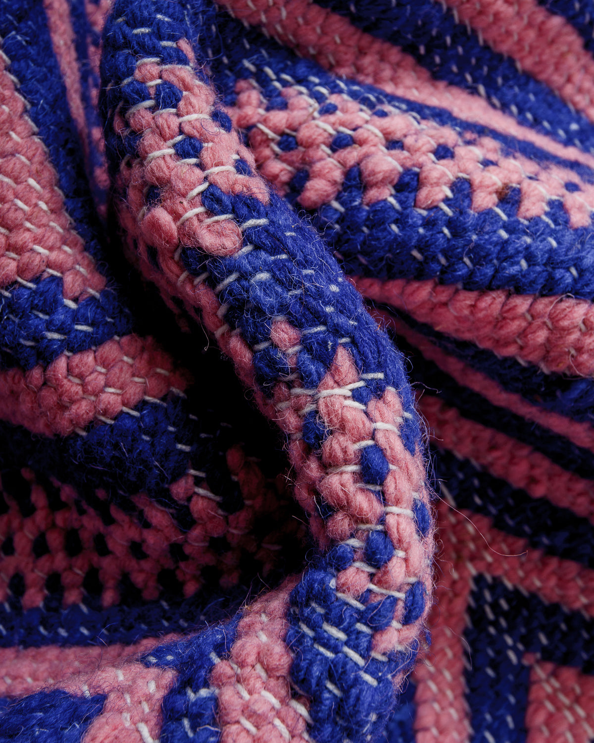 Bunched up blue and pink flat-woven kelim rug showing the texture of the weave.