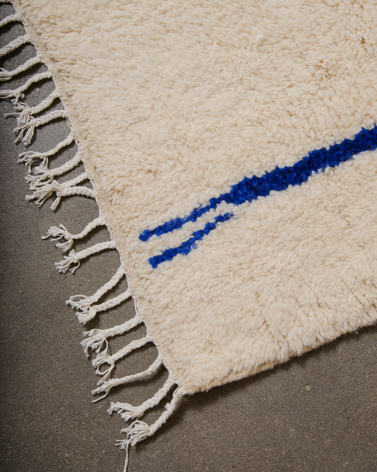 Corner of Azilal rug with white cotton tassels across the edge.