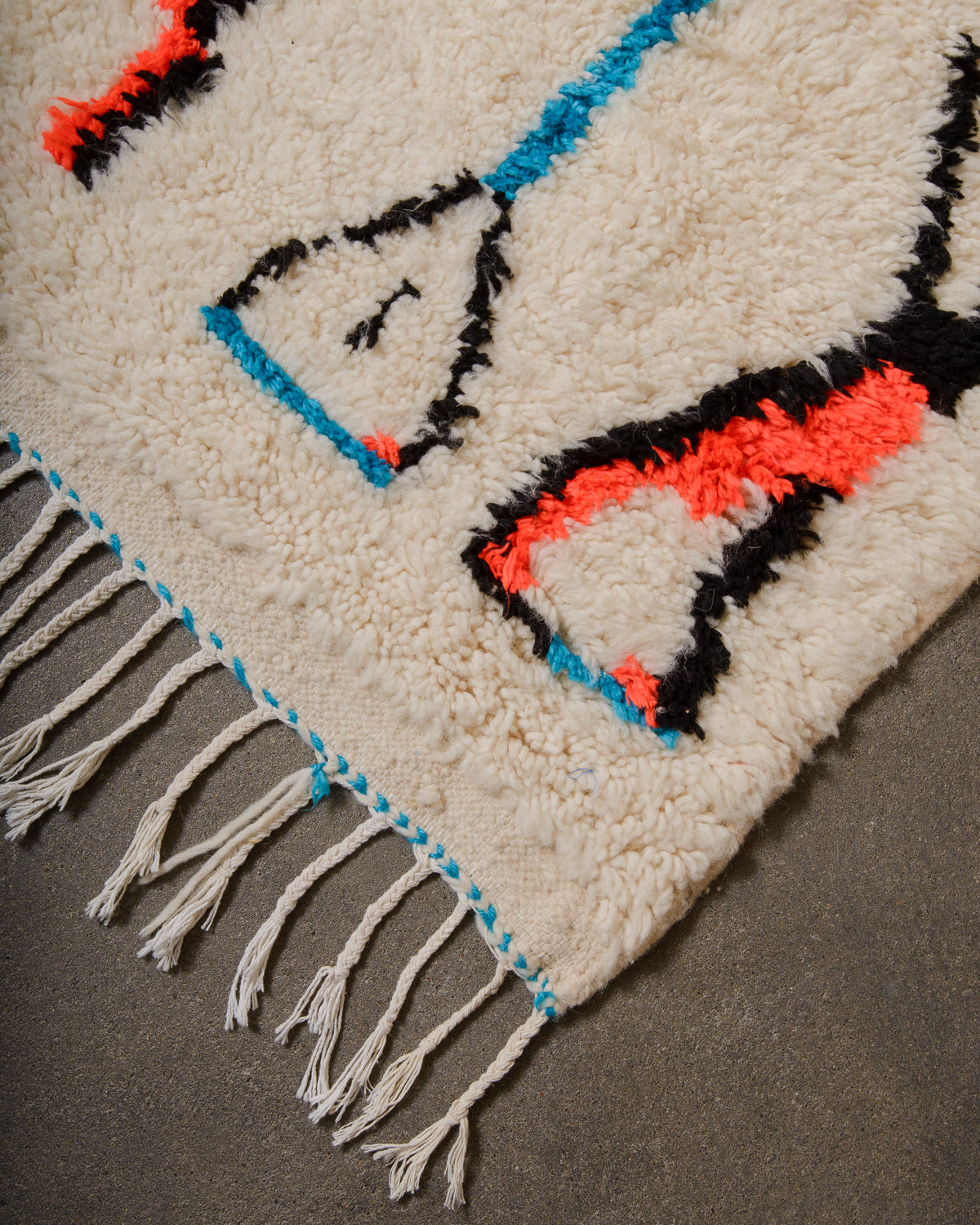 Close-up of a textured rug with geometric patterns and fringes.