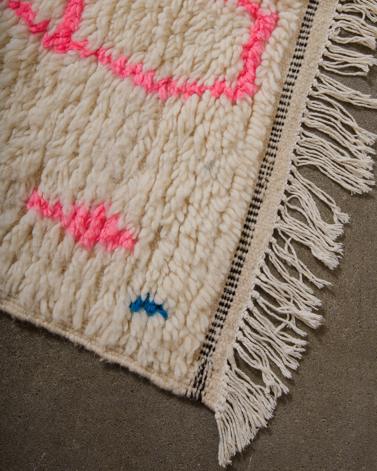 Corner of Azilal run with cream wool and white cotton tassels and black and cream weaving across the edge.