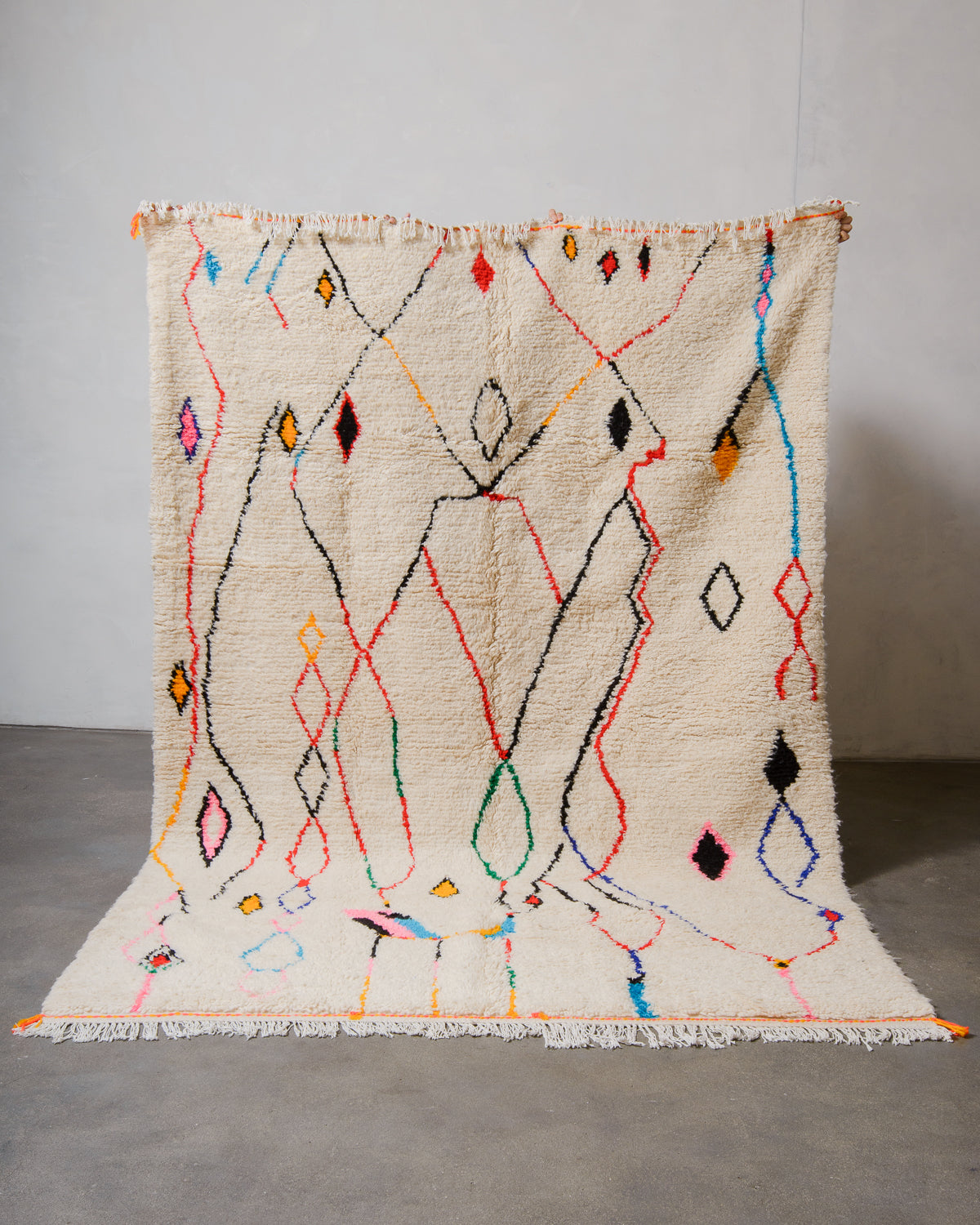 Decorative Azilal rug with colourful geometric pattern on a plain background.