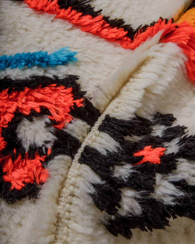 Close up of azilal rug showing fluffy pile made of cream wool and colourful cotton. 