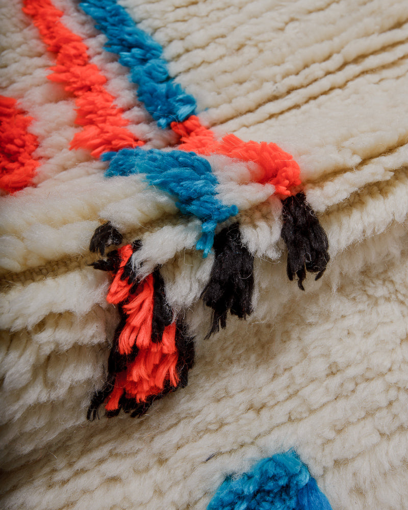 Close up of azilal rug showing fluffy pile made of cream wool and colourful cotton. 