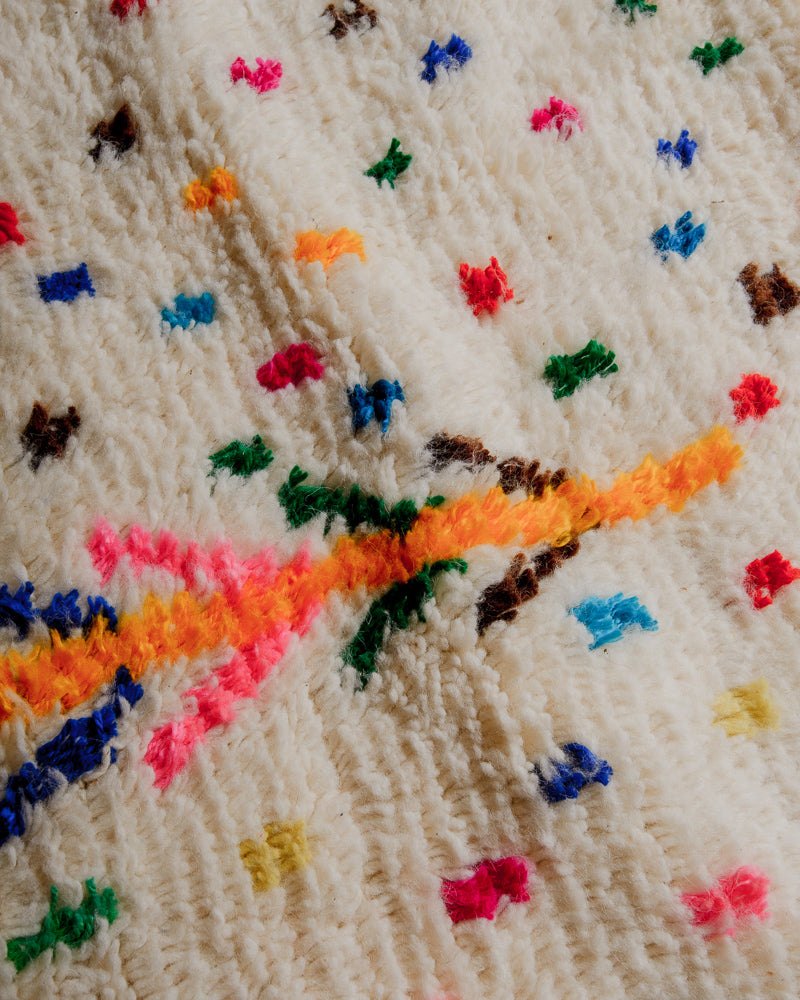 Surface of azilal rug showing soft cream wool and colourful cotton elements. 