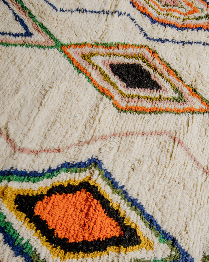 Cream surface of azilal rug with orange, yellow, blue, green and black diamonds